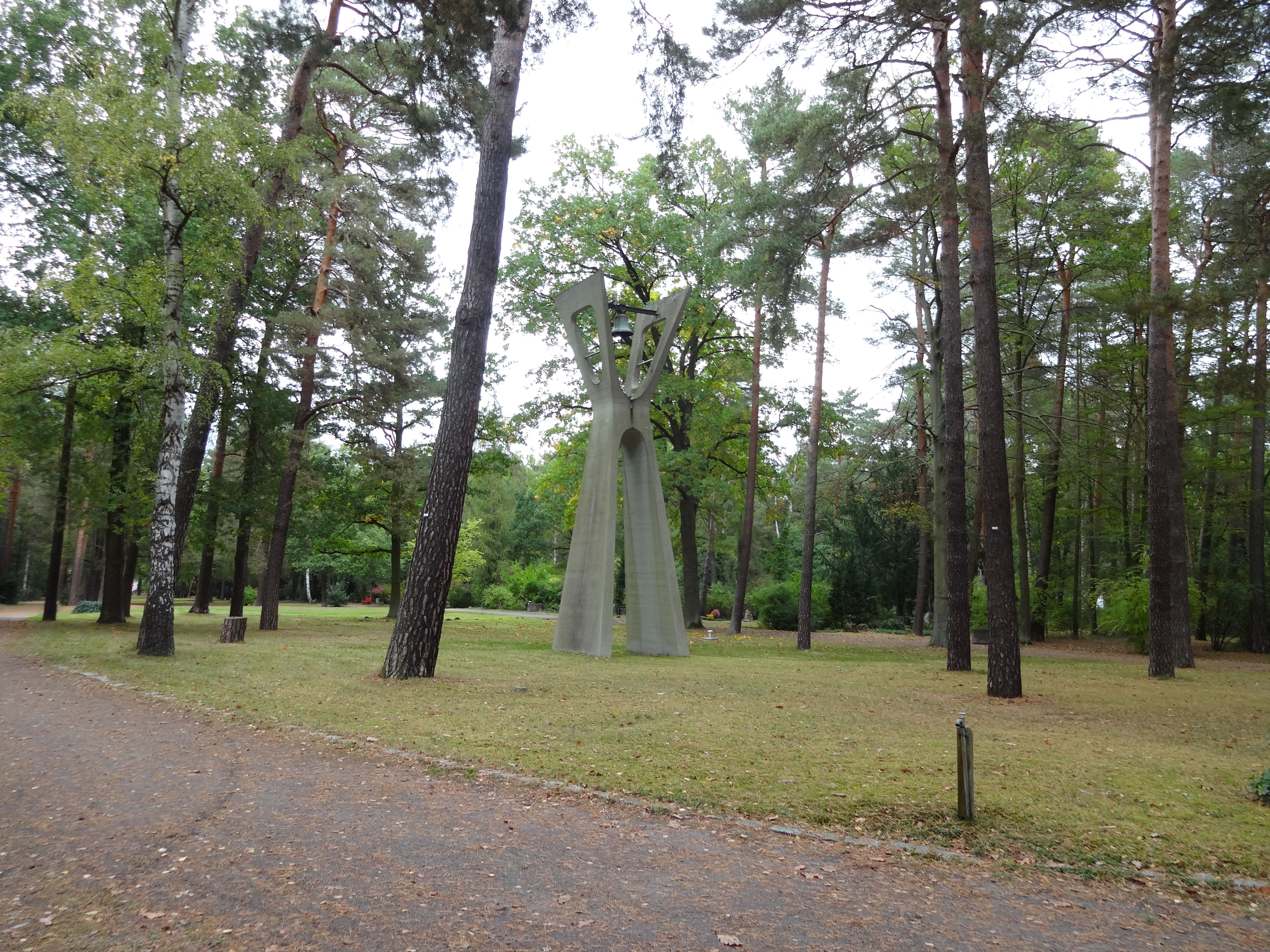 Freestanding bell tower among tall trees at Waldfriedhof Zehlendorf